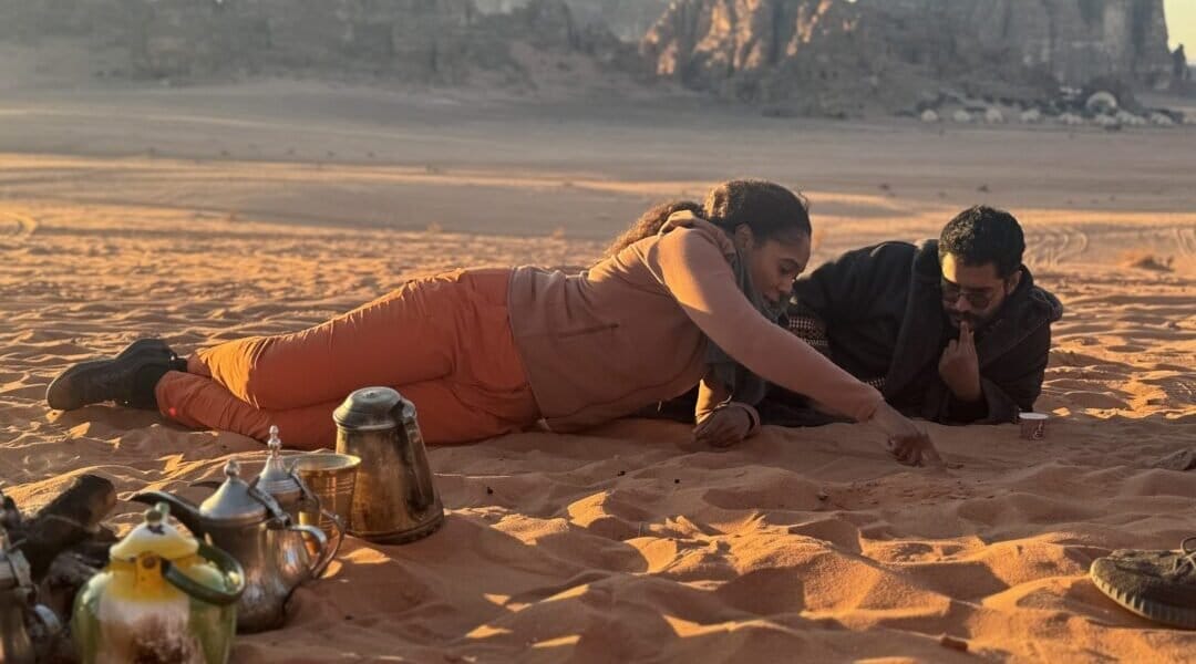 Director, Dayvee Sutton, immerses herself completely, lying on the sand, Bedouin style, playing childhood games with guide and fixer, Yanal. 